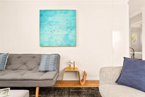 悉尼Chic apartment footsteps from Manly Beach的客厅配有沙发和墙上的绘画