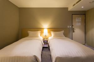 高雄麗馨商旅七賢館的两张床位于带灯的房间。