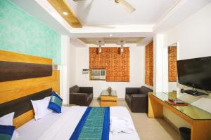 新德里Hotel Lav-Kush的客房设有床、书桌和电视。