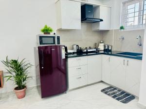 班加罗尔Olive Serviced Apartments BTM Layout的厨房配有紫色冰箱和微波炉