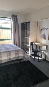 布伦海姆Tō Tātou Kainga的一间卧室配有一张床、一张书桌和一个窗户。