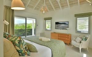 Saint BarthelemyLuxury Vacation Villa 11的一间卧室配有一张床、一台电视和一把椅子