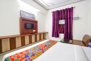 阿格拉FabHotel Prashant Palace的一间卧室配有一张床和一台电视。