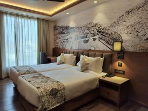 斋浦尔Hotel Royal Lakshmi Palace的酒店客房设有两张床,墙上挂有绘画作品