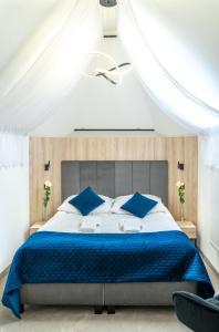 什切尔克阿尔品酒店的一间卧室配有一张带蓝色枕头的大床