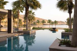 马斯喀特Jumeirah Muscat Bay的棕榈树和水体的游泳池