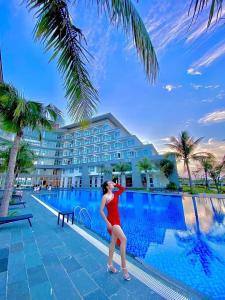 洞海Duy Tân Quảng Bình Hotel & Resort的身着红色衣服的女人站在游泳池边