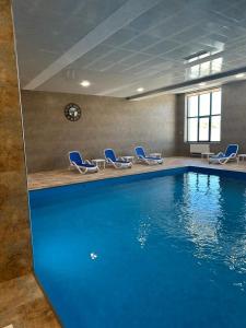 萨克德佐尔镇Alvina complex的一个带蓝色椅子的游泳池以及一个大型游泳池