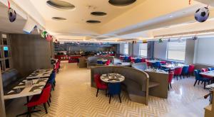 勒克瑙Ramada by Wyndham Lucknow Hotel and Convention Center的一间带桌椅的用餐室和一间餐厅