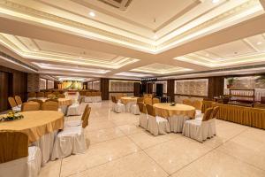 勒克瑙The Elite Lucknow Convention Hotel的宴会厅配有圆桌和椅子