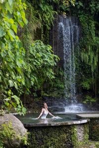 苏卡瓦提圣曼陀罗别墅及温泉酒店的瀑布前的游泳池游泳的女人