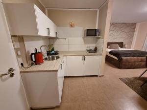 上乌瑟尔玉兰公寓式酒店的一间厨房,配有白色的橱柜和一张位于客房内的床
