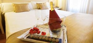 洛格罗尼奥孔德斯哈罗酒店的床上的托盘,上面放着两杯酒和蜡烛