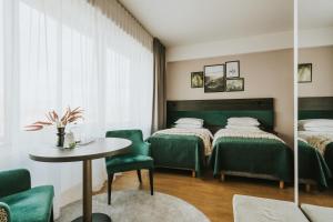 伊诺弗罗茨瓦夫Green Hotel的一间设有两张床和一张桌子及椅子的房间