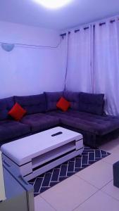 ThikaSerene Safaris Airbnb in Thika的客厅配有带红色枕头的紫色沙发