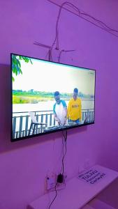 ThikaSerene Safaris Airbnb in Thika的紫色墙上的电视,上面有两个人