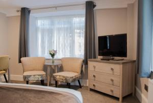 阿斯顿尖塔霍尔特酒店的一间卧室配有电视和桌椅