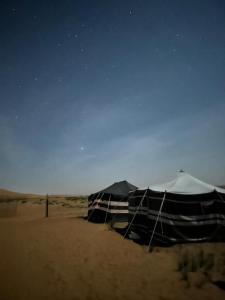 BadīyahSandGlass Camp的夜晚沙漠中的黑白帐篷