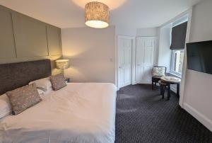 霍伊斯The White Hart Inn, Hawes的卧室配有白色的床和电视。