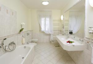卡罗维发利米尼翁酒店的一间带两个盥洗盆、浴缸和卫生间的浴室