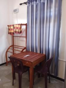 韦利格默Villa Don Williams Weligama的木桌和窗帘旁的椅子