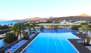 卡列罗港Hotel Costa Calero Thalasso & Spa的享有带椅子的大型游泳池和大海的顶部景致