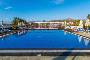 卡列罗港Hotel Costa Calero Thalasso & Spa的度假村的游泳池配有椅子和遮阳伞