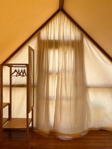 加的斯BOHO GLAMPING CONIL的帐篷内的窗户,配有白色窗帘