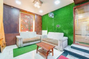 钦奈FabExpress Raj Supreme Residency的客厅配有两把椅子和绿色的墙壁