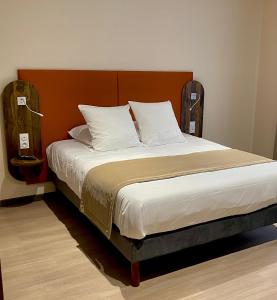 诺让-巴西尼Hôtel du Commerce-restaurant au Couteau的一间卧室配有一张大床和木制床头板