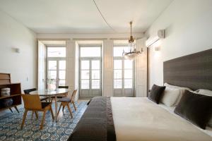 波尔图Palácio Fenizia Lux Apartments的一间卧室配有一张大床和一张桌子及椅子