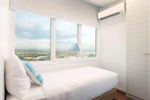 纳仲天ไวท์ แซนด์ บีช เรสซิเดนซ์ พัทยา(White Sand Beach Residences Pattaya)的白色卧室设有大窗户和一张床
