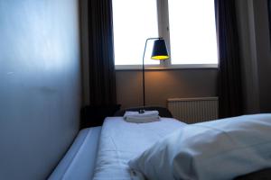 玛丽斯塔德Vänerport Stadshotell i Mariestad的一间卧室配有一张带灯和窗户的床