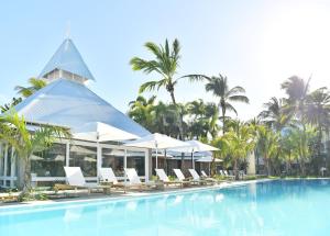 格兰贝伊维兰达大湾酒店及水疗中心的度假村的游泳池配有白色椅子和遮阳伞