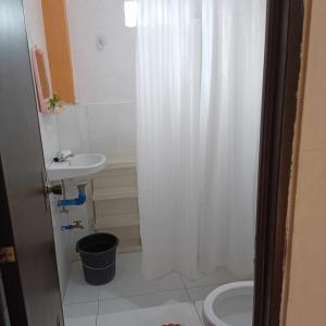 BarasTitaays Surfers Inn的浴室设有白色的淋浴帘和水槽