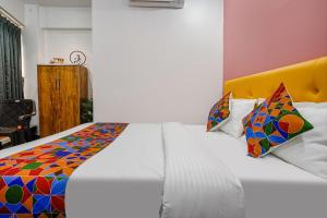 苏拉特FabHotel Sky City的一间卧室配有一张带彩色被子的白色床