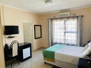 哈博罗内Phase 4: 5 Bed luxury Villa的一间卧室配有一张床、一台电视和一个窗口