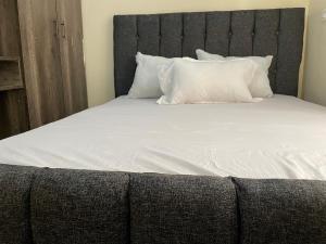 Kitengela SNOWHAVEN BnB Kitengela的一张配有白色床单和枕头的大床