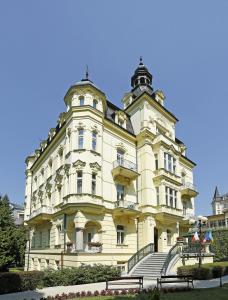 卡罗维发利米尼翁酒店的一座黄色的大建筑,前面有楼梯