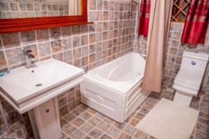 恩德培Hidden Treasure Serviced Hotel Apartments HITSHA HOTELS Entebbe的一间带水槽、浴缸和卫生间的浴室