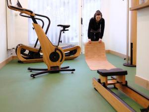 普瓦捷Logis Hôtel de l'Europe的一名妇女站在健身房里,有几个健身器材