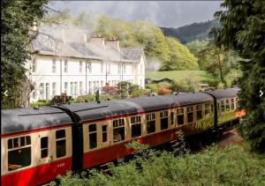 纽比桥Steam Train Cottage - Lake District Hideaway的房屋前的轨道上的火车