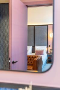 里斯本The Editory Riverside Hotel, an Historic Hotel的镜子反射着一间卧室,卧室配有一张床和一张沙发
