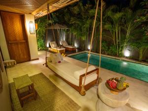 吉利特拉旺安Cocana Resort Gili Trawangan的一间带秋千床的卧室和一个游泳池