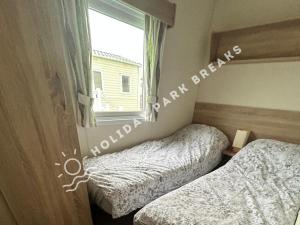 塞尔西Cosy 2 bed @ Seal Bay, Selsey的卧室设有两张床,带窗户