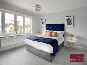 泰晤士迪顿Thames Ditton - Luxury 4 Bedroom House - Garden and Parking的一间卧室配有一张大床和蓝色床头板