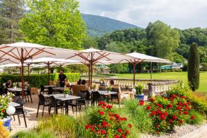 于尔亚日莱班Grand Hôtel & Spa Uriage的花园内带桌子和遮阳伞的餐厅