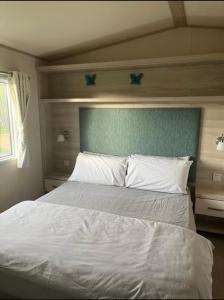 坦伯利GDs Luxury Caravan Hire Turnberry Holiday Park的一间卧室配有一张白色的床和蓝色床头板