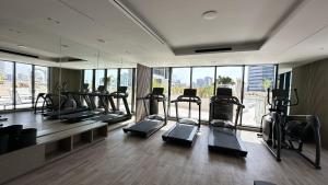 迪拜EasyGo - Binghatti Luna Stylish 1BR的一个带跑步机和椭圆机的健身房,位于带窗户的房间内