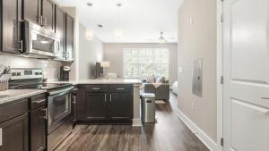 夏洛特Landing Modern Apartment with Amazing Amenities (ID9577X84)的一间带棕色橱柜的厨房和一间带沙发的厨房